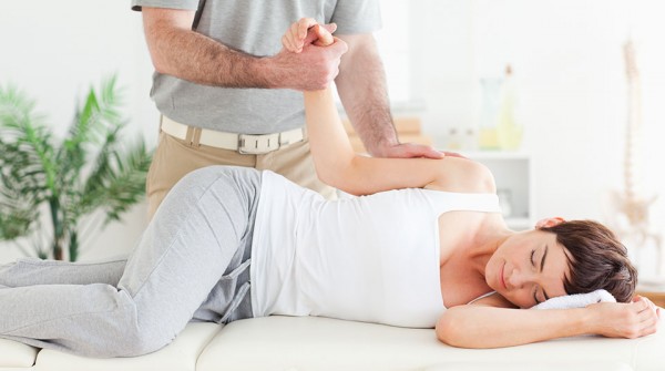 Chiropractor stretches female customer's arm