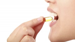 woman putting a transparent pill into her mouth