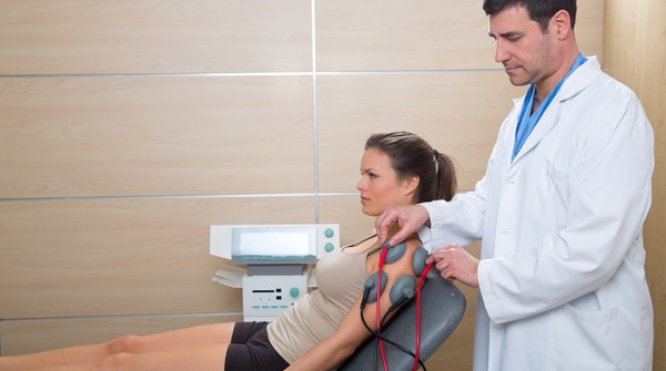 Doctor therapist checking muscle electrostimulation to woman