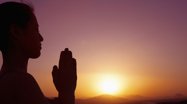 Serene young woman doing prayer pose in the desert
